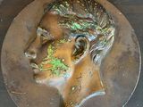 une tête d'homme en bronze posée sur une table en bois