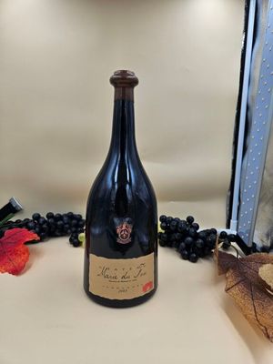 une bouteille de vin posée sur un comptoir, à côté d'une grappe de raisin