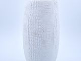 un vase blanc posé sur une surface blanche
