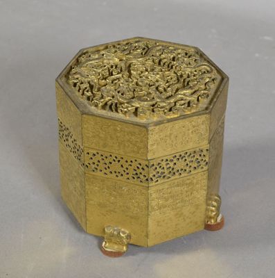 une boîte dorée ornée d'un motif sur un fond blanc