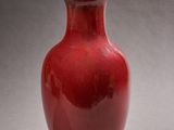un vase rouge muni d'un couvercle en bois, posé sur une table