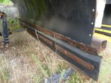 a black boat sitting in the grass next to a yellow truck