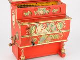 un piano rouge orné d'une peinture sur le couvercle