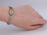wrist of a woman with a watch on her wrist on a white surface