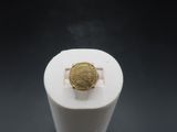 une image représentant une bague en or posée sur un objet blanc