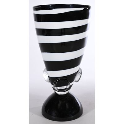 un vase en verre rayé noir et blanc posé sur un socle