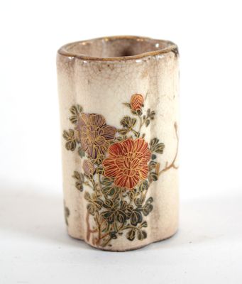 un petit vase orné de fleurs, posé sur une surface blanche