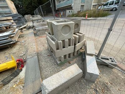 un tas de parpaings posés par terre près d'une clôture
