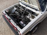 a white car with an open hood sitting in the dirt