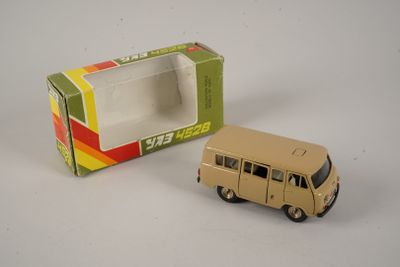 un petit bus en jouet posé devant une boîte