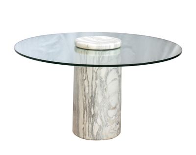 La table est en marbre et possède un plateau en verre.