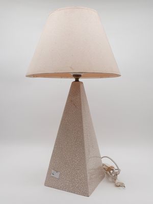 the lamp is sitting on a white surface with a beige shade on it