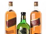 three bottles of alcohol are lined up on a white surface