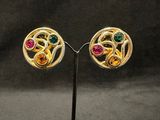 a pair of gold earrings with multi colored stones on a stand