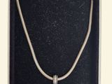 an open box with a silver bracelet and a heart charm