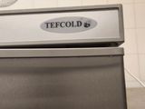 a stainless steel refrigerator in a kitchen with a fan in the background