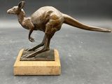bronze statue of a kangaroo on a wooden base on a gray background