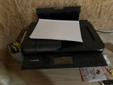 une imprimante posée sur un bureau, à côté d'une pile de papiers
