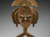 un masque en bois posé sur un socle et représentant un visage