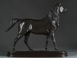 bronze statue of a horse on a wooden base against a gray background