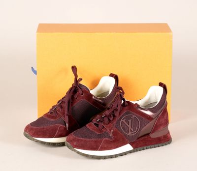 Les baskets rouges se trouvent à côté d'une boîte jaune posée sur une surface blanche.