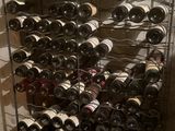 bottles of wine are stacked on a metal rack in a wine cellar