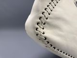 gros plan sur un sac à main en cuir blanc avec des coutures noires à l'intérieur