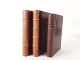 two old books sitting on top of each other on a white surface