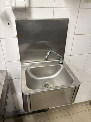 un évier en acier inoxydable dans le coin d'une toilette publique