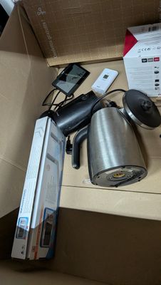 une boîte contenant une cafetière, une télécommande, un téléphone portable et d'autres objets