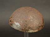 a rusted helmet on a metal stand against a black background