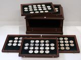 three wooden boxes with silver coins in them sitting on a white surface