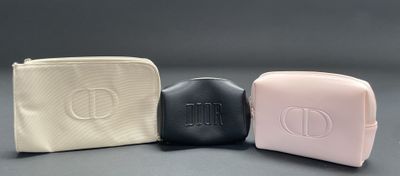 three cosmetic bags are lined up on a gray surface