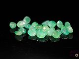 a close up of a bunch of green gems on a black surface