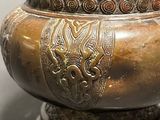 a large bronze vase with a lid on a table