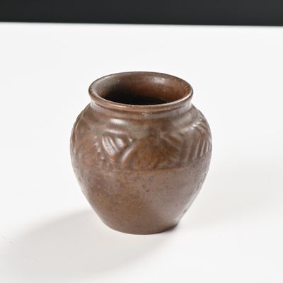 un petit vase marron posé sur une table blanche
