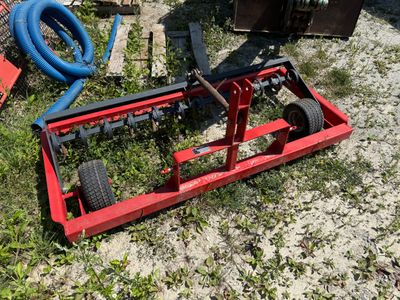 a red and black machine sitting on the ground next to a blue hose