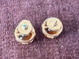 two gold colored buttons sitting on a purple surface
