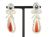 une photo d'une paire de boucles d'oreilles ornées de pierres orange et bleues