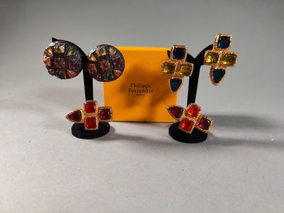 a pair of earrings with colorful stones on them sitting next to a yellow box