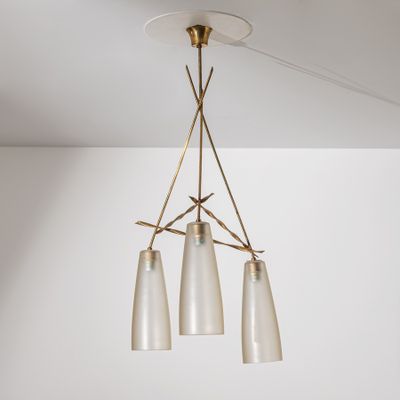 un lustre en laiton muni de trois abat-jours en verre suspendu au plafond