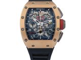 La montre est dorée et noire, avec une trotteuse rouge