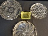 trois assiettes en verre et un récipient en verre posés sur une table