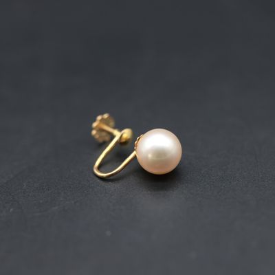 a pair of pearl earrings on a black surface