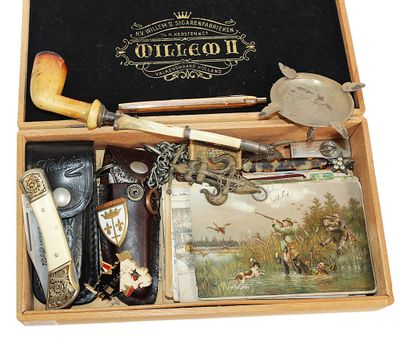 une boîte en bois contenant divers objets, tels qu'une pipe, un couteau, un portefeuille et d'autres objets