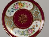 a red plate with a gold border and flowers on it