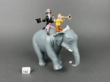 figurines of two people riding on top of an elephant with a trumpet