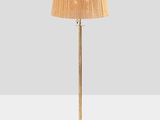 a gold floor lamp with a beige shade on top of it