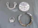 une broche en argent, une bague et deux autres objets posés sur une table
