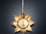 a close up of a gold sunflower ornament hanging on a black background